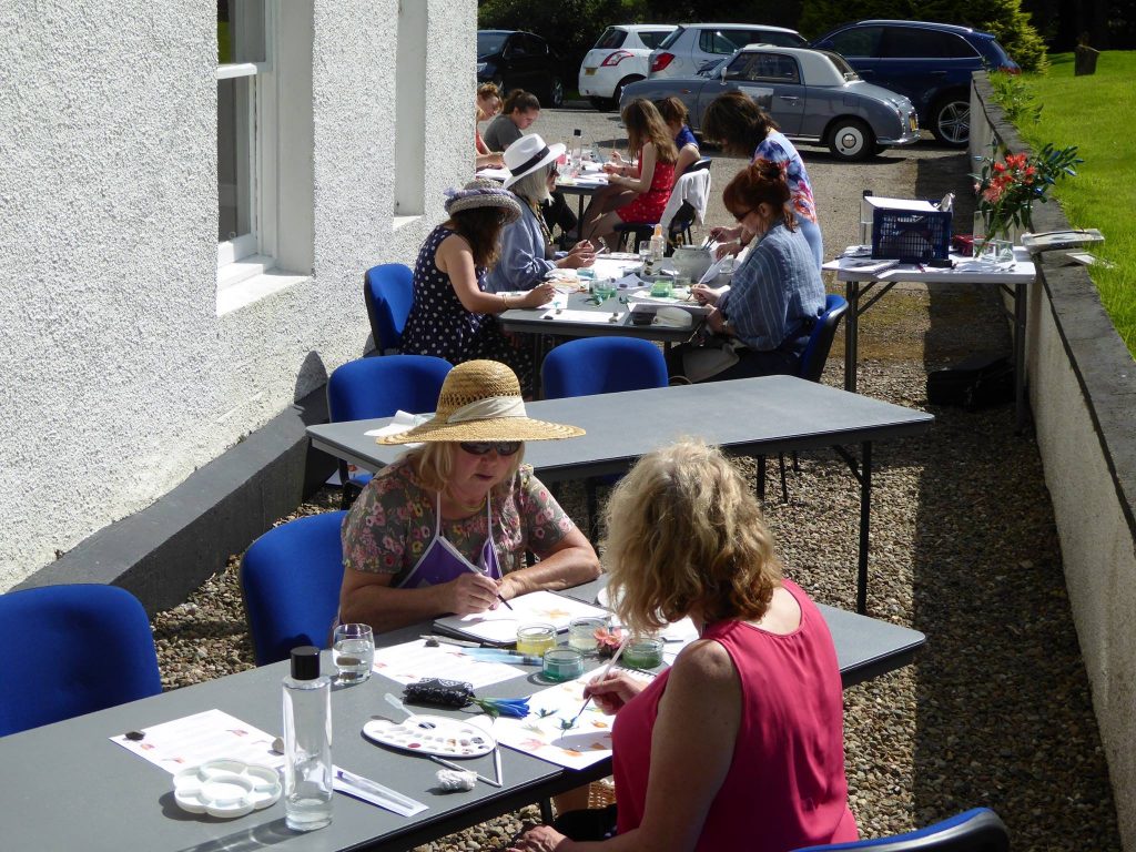 ladies painting outside in sunhats at the Saplinbrae hotel, Mintlaw at an Afternoon tea and watercolours day.